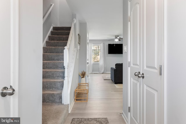 stairs featuring baseboards, ceiling fan, and wood finished floors