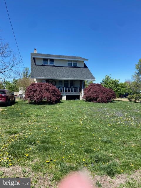 view of front of house featuring a chimney, a porch, and a front yard