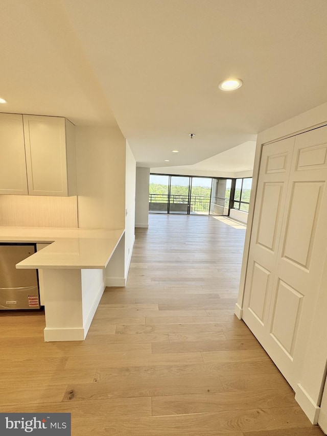 hallway featuring recessed lighting, light wood-style floors, baseboards, and expansive windows