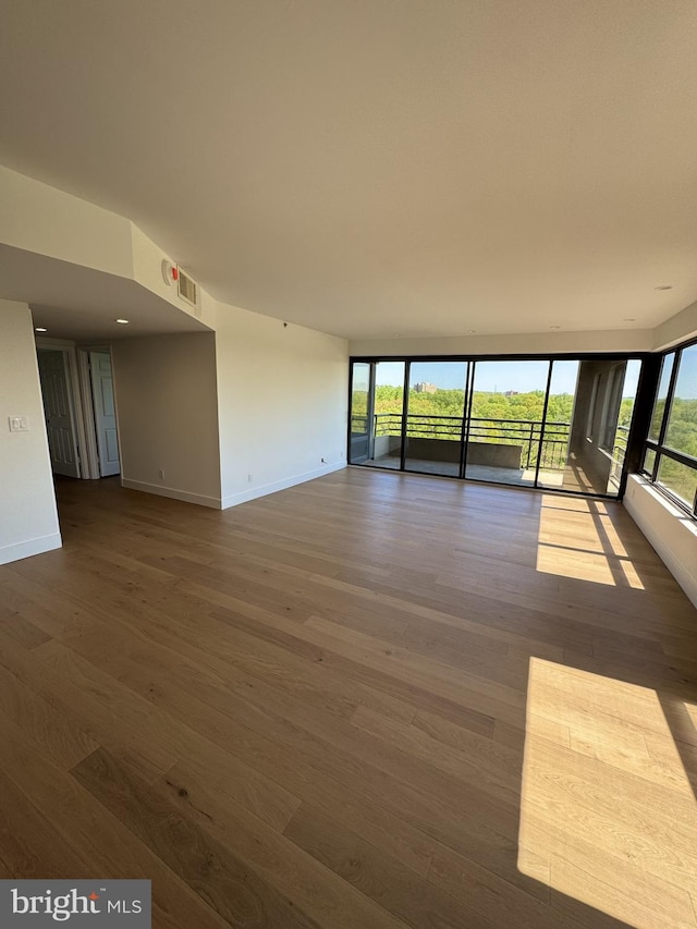 unfurnished room with baseboards, dark wood-style flooring, and a wealth of natural light