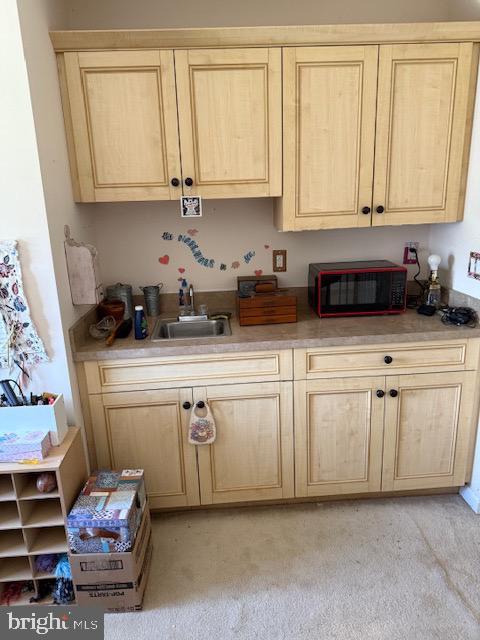 kitchen featuring a sink, light brown cabinetry, black microwave, and light countertops