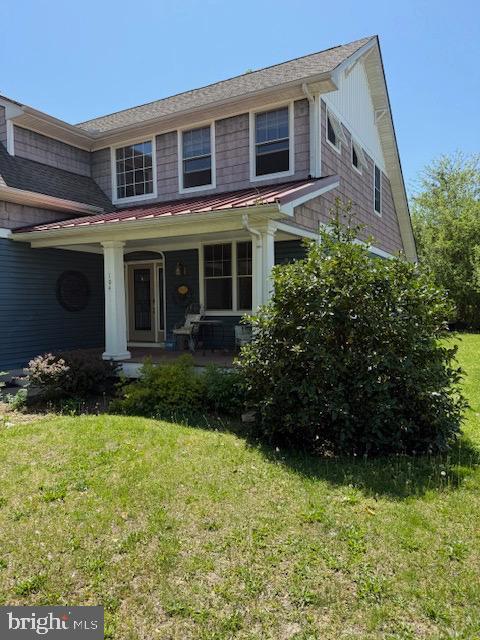 traditional-style home featuring a porch, a standing seam roof, and a front yard