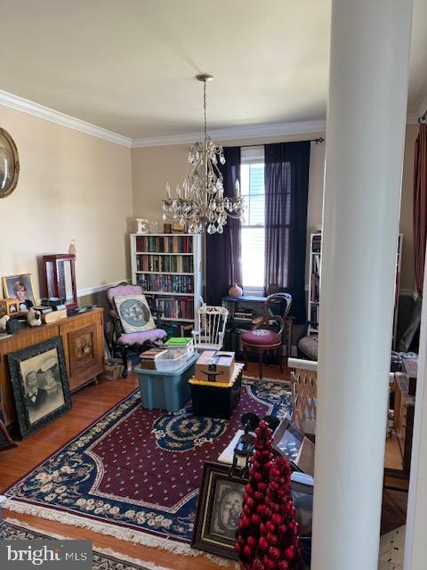 interior space with crown molding, a chandelier, decorative columns, and wood finished floors