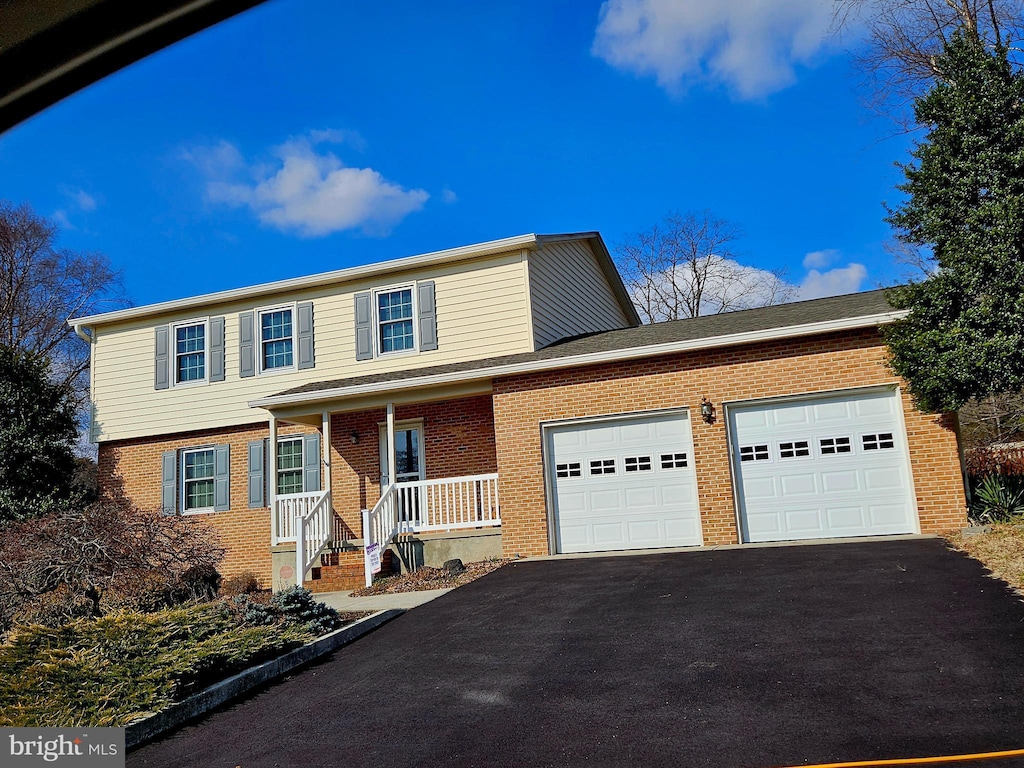 traditional home featuring brick siding, a garage, and aphalt driveway