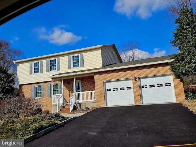 traditional home featuring brick siding, a garage, and aphalt driveway