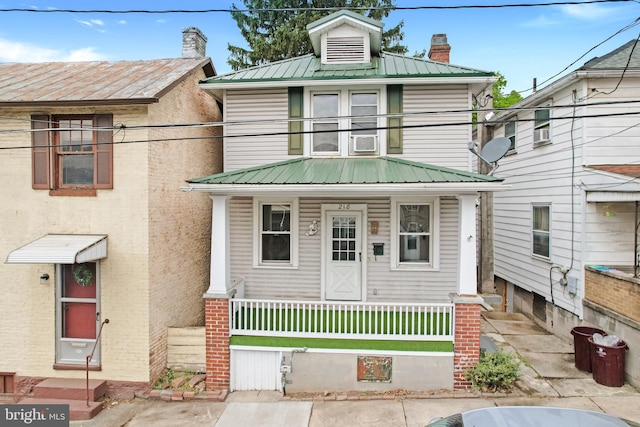 traditional style home featuring a front lawn, a balcony, metal roof, a porch, and a fenced front yard