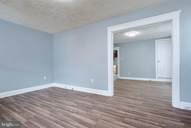 unfurnished room featuring a textured ceiling, baseboards, and wood finished floors