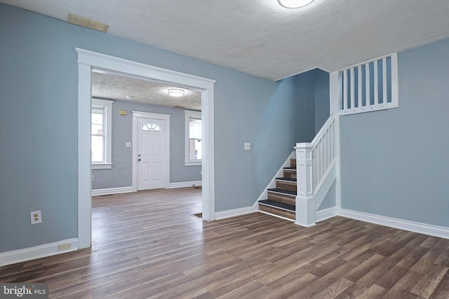 entrance foyer with baseboards, a textured ceiling, dark wood-style flooring, and stairs