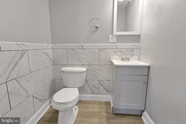 bathroom featuring vanity, toilet, wood finished floors, and tile walls