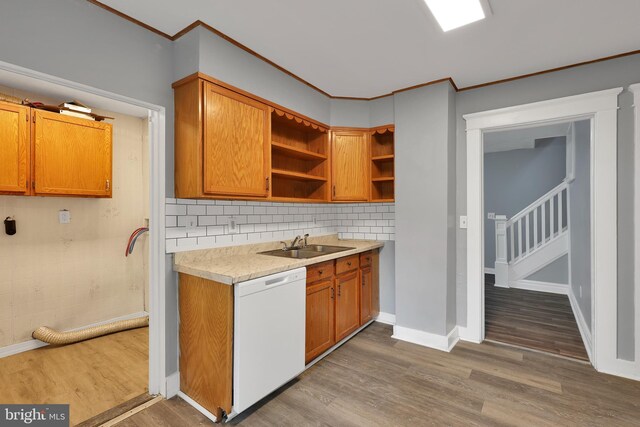kitchen featuring crown molding, a sink, dishwasher, light countertops, and wood finished floors