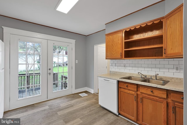 kitchen featuring open shelves, a sink, dishwasher, light wood-type flooring, and backsplash