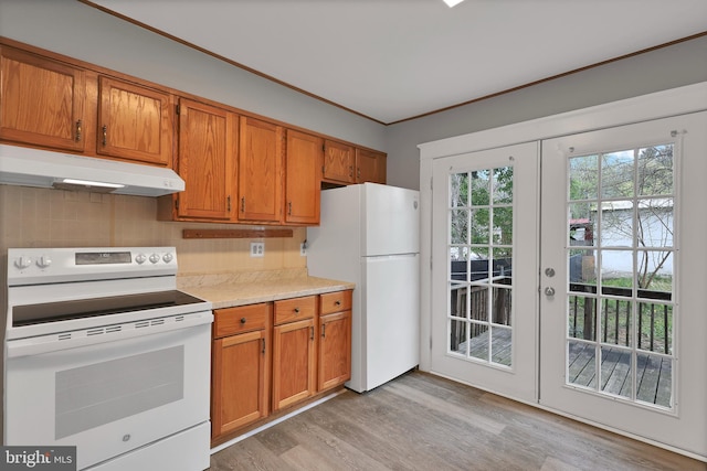kitchen with brown cabinets, light wood-type flooring, light countertops, under cabinet range hood, and white appliances