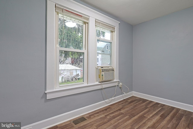 empty room featuring baseboards, cooling unit, dark wood-type flooring, and visible vents
