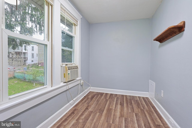 unfurnished room with baseboards, cooling unit, and wood finished floors