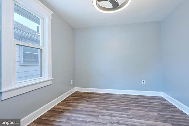 spare room featuring baseboards and dark wood-style floors