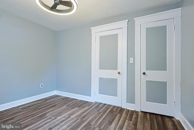 spare room featuring baseboards and dark wood-style floors