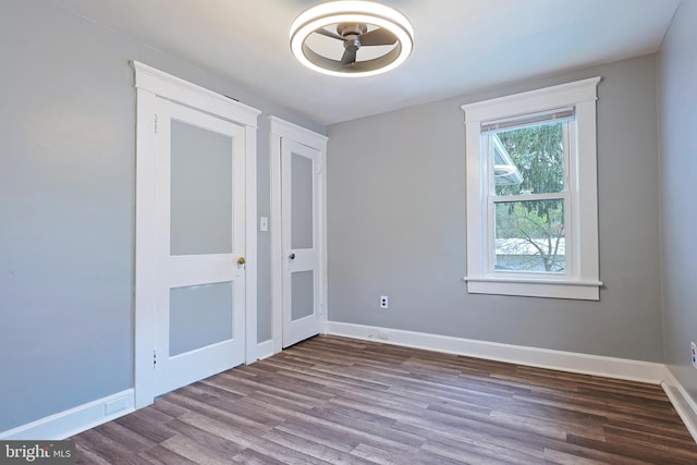 unfurnished room featuring baseboards, ceiling fan, and dark wood-type flooring