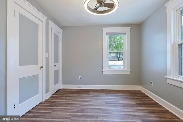 unfurnished bedroom with baseboards and dark wood-type flooring