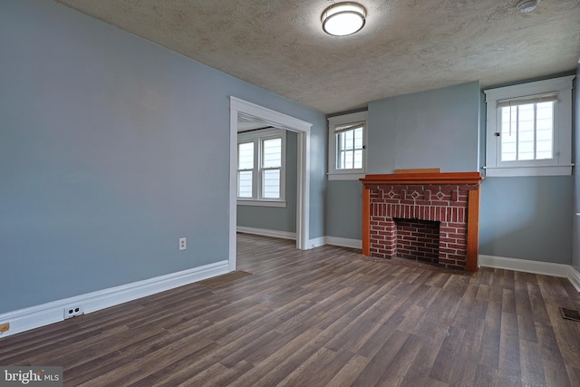 unfurnished living room with baseboards, a textured ceiling, a brick fireplace, and wood finished floors