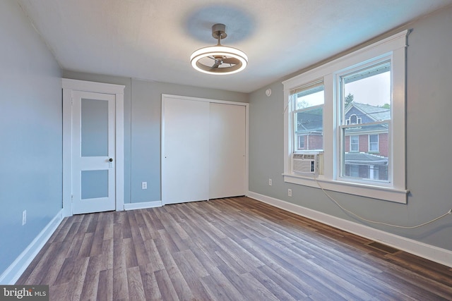 unfurnished bedroom featuring baseboards, wood finished floors, and a closet