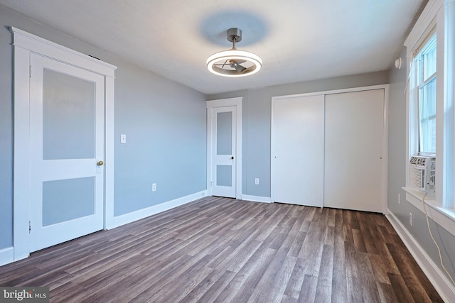 unfurnished bedroom with cooling unit, baseboards, wood finished floors, and a closet