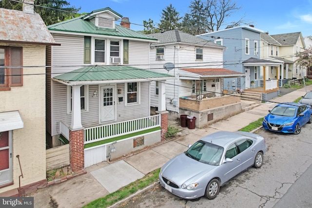 view of front of house with a porch, a residential view, and metal roof