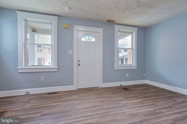entrance foyer featuring visible vents, a textured ceiling, baseboards, and wood finished floors