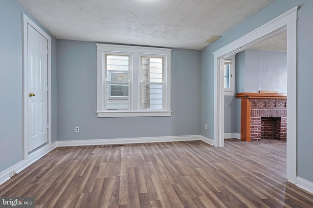 unfurnished living room featuring a textured ceiling, baseboards, wood finished floors, and a fireplace
