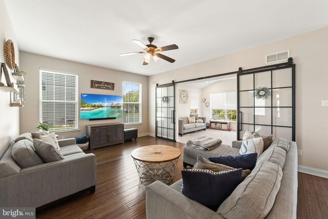 living room featuring ceiling fan, visible vents, a barn door, and plenty of natural light