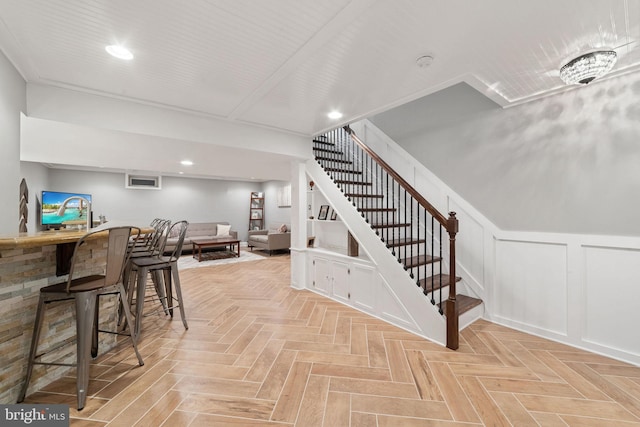 interior space with recessed lighting, wet bar, a wainscoted wall, and a decorative wall