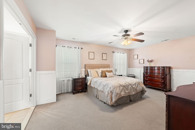 bedroom featuring carpet floors, wainscoting, ceiling fan, and visible vents