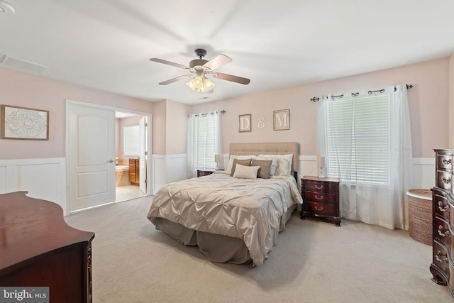 bedroom with connected bathroom, ceiling fan, wainscoting, carpet floors, and visible vents