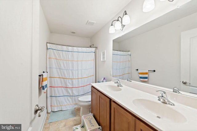 full bath featuring double vanity, toilet, visible vents, and a sink