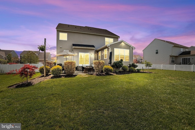 back of property at dusk featuring a lawn, a patio, and a fenced backyard