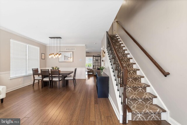 interior space with visible vents, ornamental molding, hardwood / wood-style floors, baseboards, and stairway