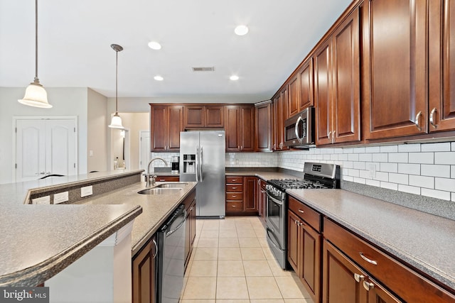 kitchen with light tile patterned flooring, a sink, stainless steel appliances, decorative light fixtures, and decorative backsplash