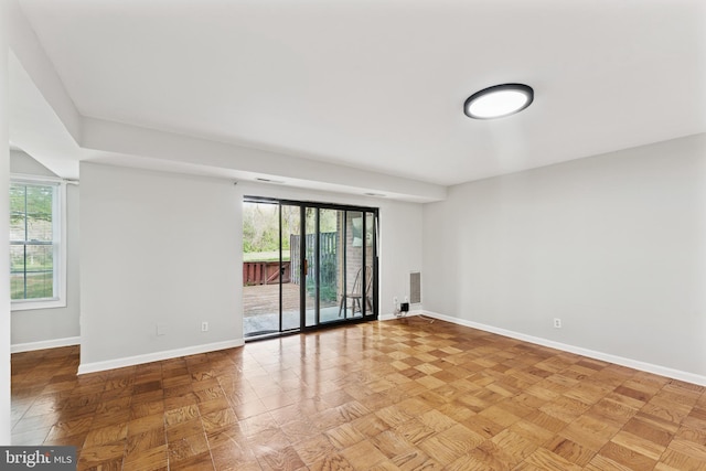 empty room with a healthy amount of sunlight, baseboards, and visible vents