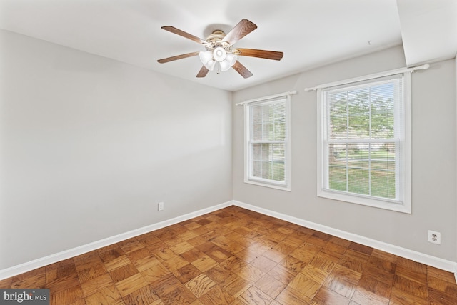 spare room with a ceiling fan and baseboards