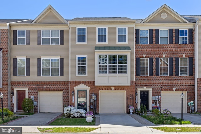 view of property with an attached garage, driveway, and brick siding