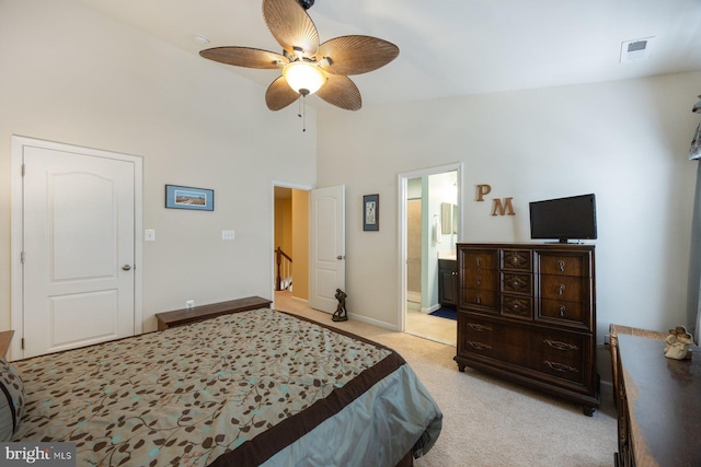 bedroom with visible vents, light carpet, baseboards, ceiling fan, and ensuite bath