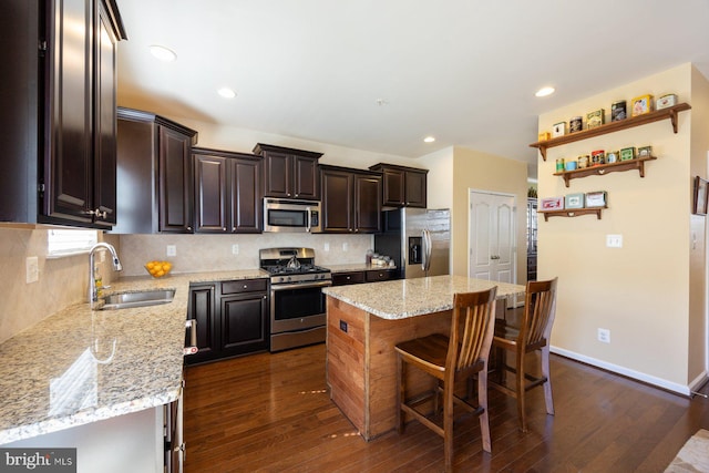 kitchen with backsplash, stainless steel appliances, light stone countertops, and a sink
