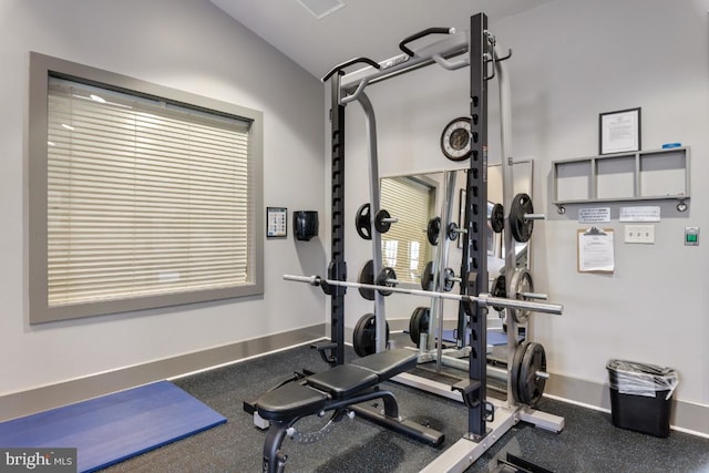 exercise area featuring baseboards and lofted ceiling
