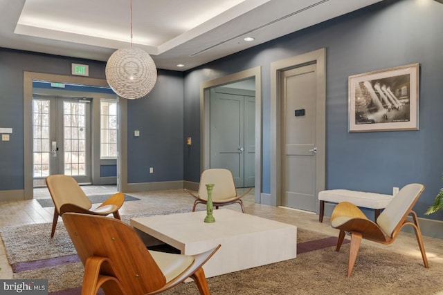 living area with light wood-style floors, french doors, recessed lighting, baseboards, and a tray ceiling