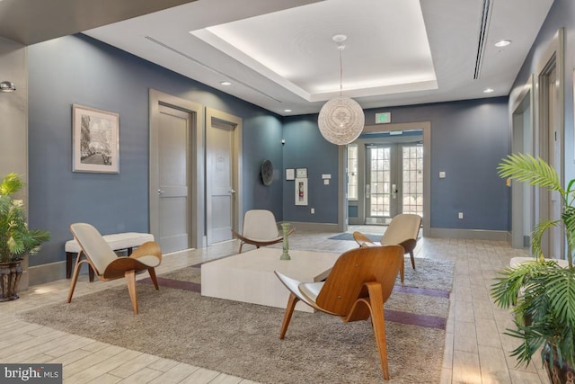 living area with recessed lighting, baseboards, wood finished floors, and a raised ceiling