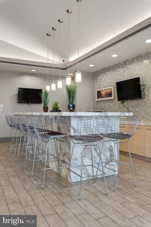 bar with indoor wet bar, recessed lighting, hanging light fixtures, and light wood-style flooring