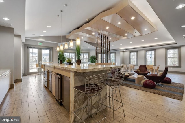 kitchen featuring baseboards, a breakfast bar area, wood finish floors, and a healthy amount of sunlight