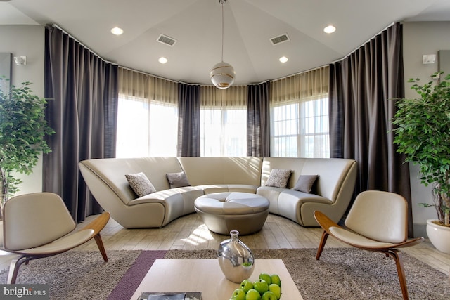 living area featuring visible vents, lofted ceiling, and a wealth of natural light
