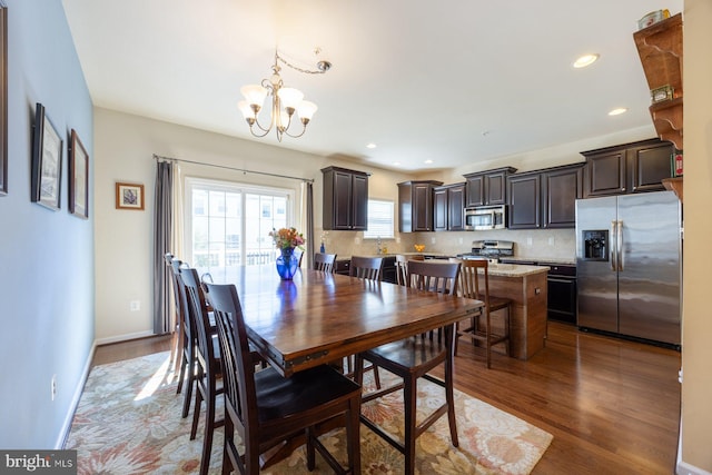 dining space featuring baseboards, recessed lighting, wood finished floors, and a chandelier