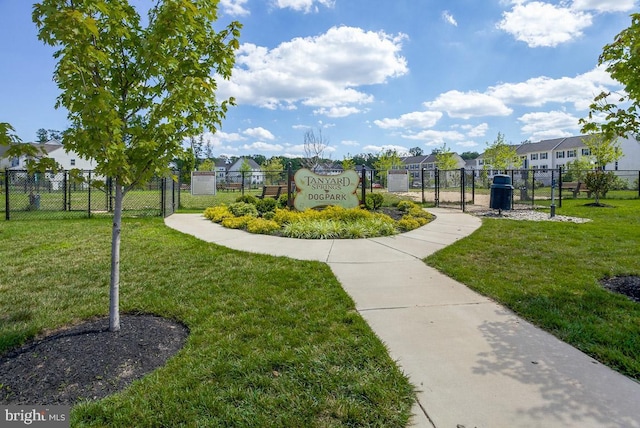 view of community with a gate, fence, a yard, and a residential view