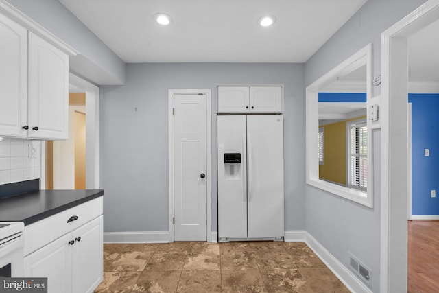 kitchen featuring visible vents, white cabinets, white refrigerator with ice dispenser, and dark countertops